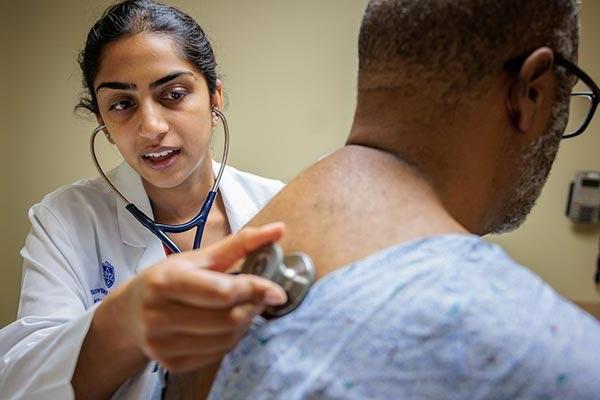 Medical students examine a standardized patient.